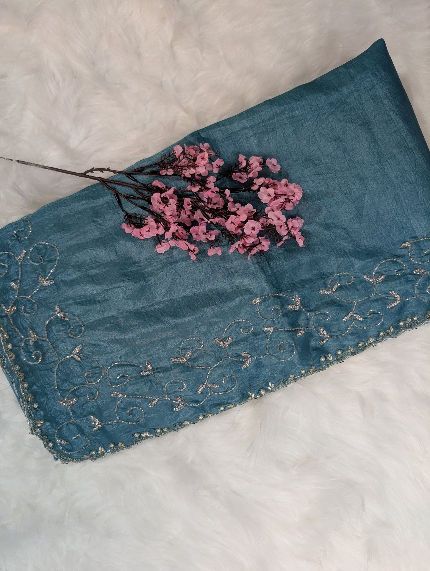 Blue embroidered fabric with pink flowers on a white background