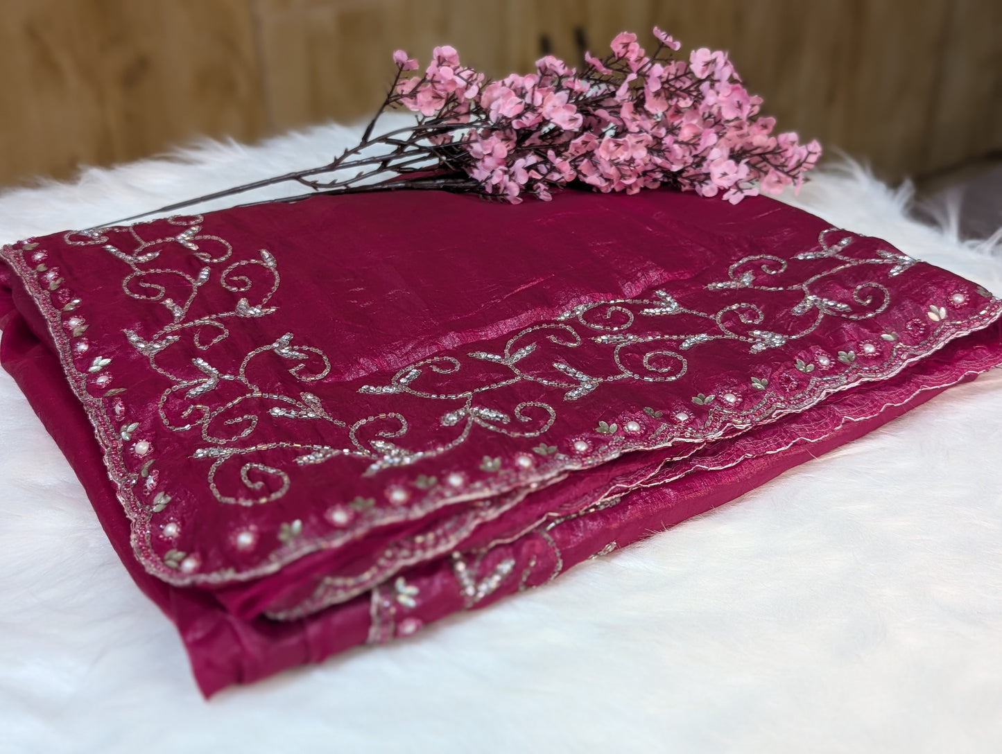 Embroidered pink fabric with floral decorations on a white surface