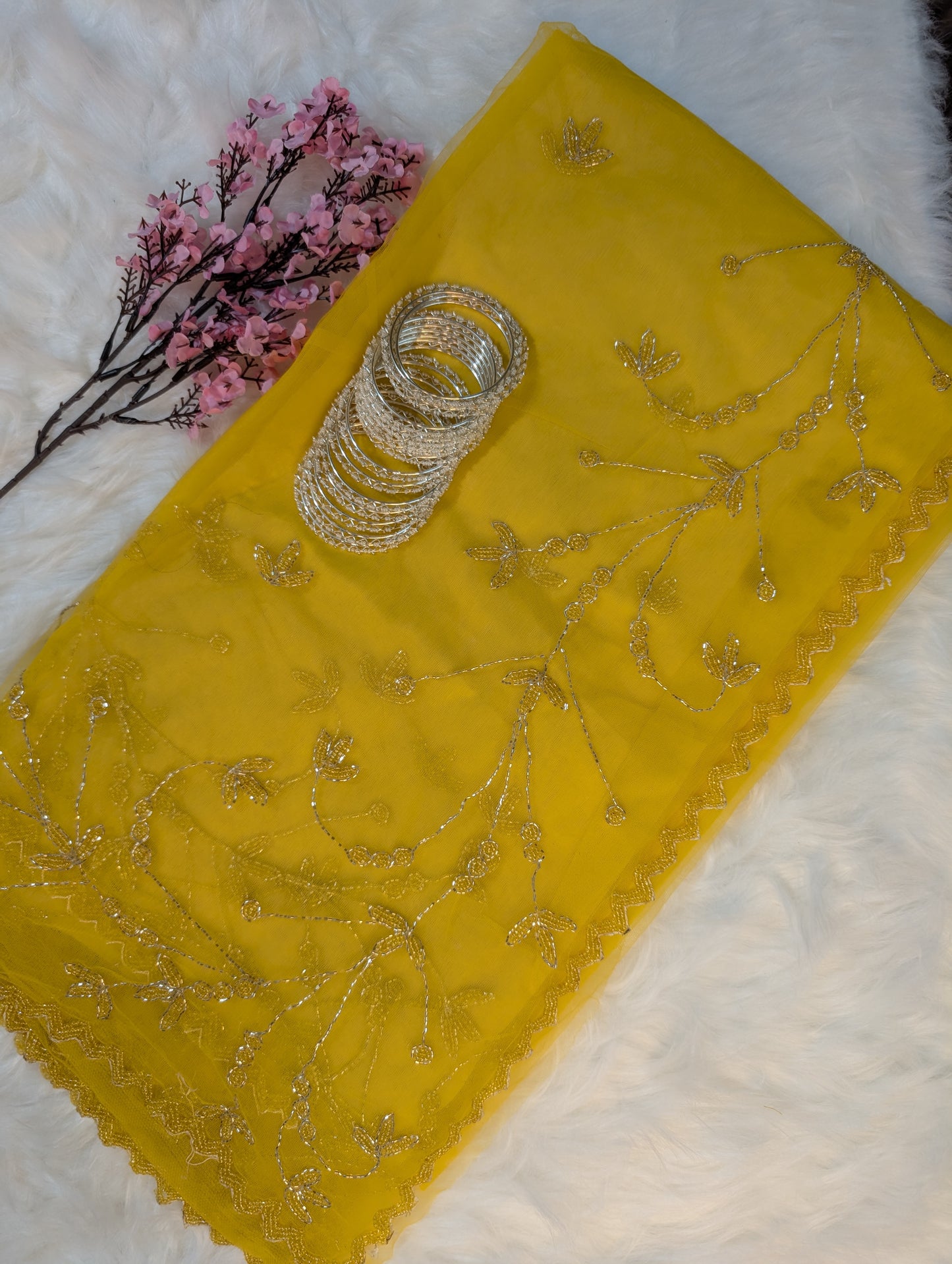 Yellow embroidered fabric with gold thread on a white background