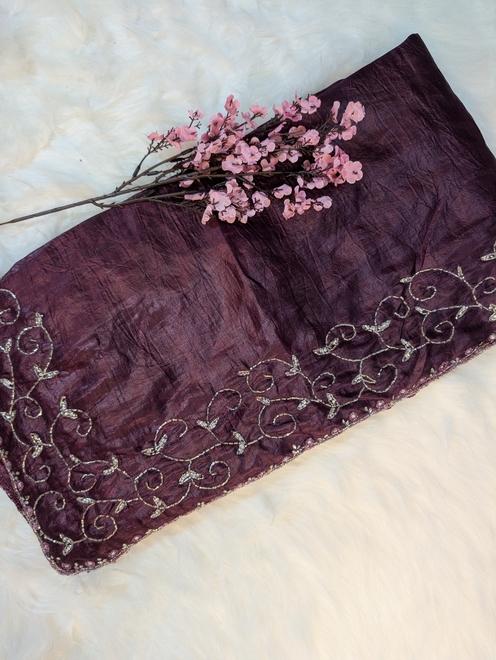 Purple clutch with floral embellishments on a textured surface