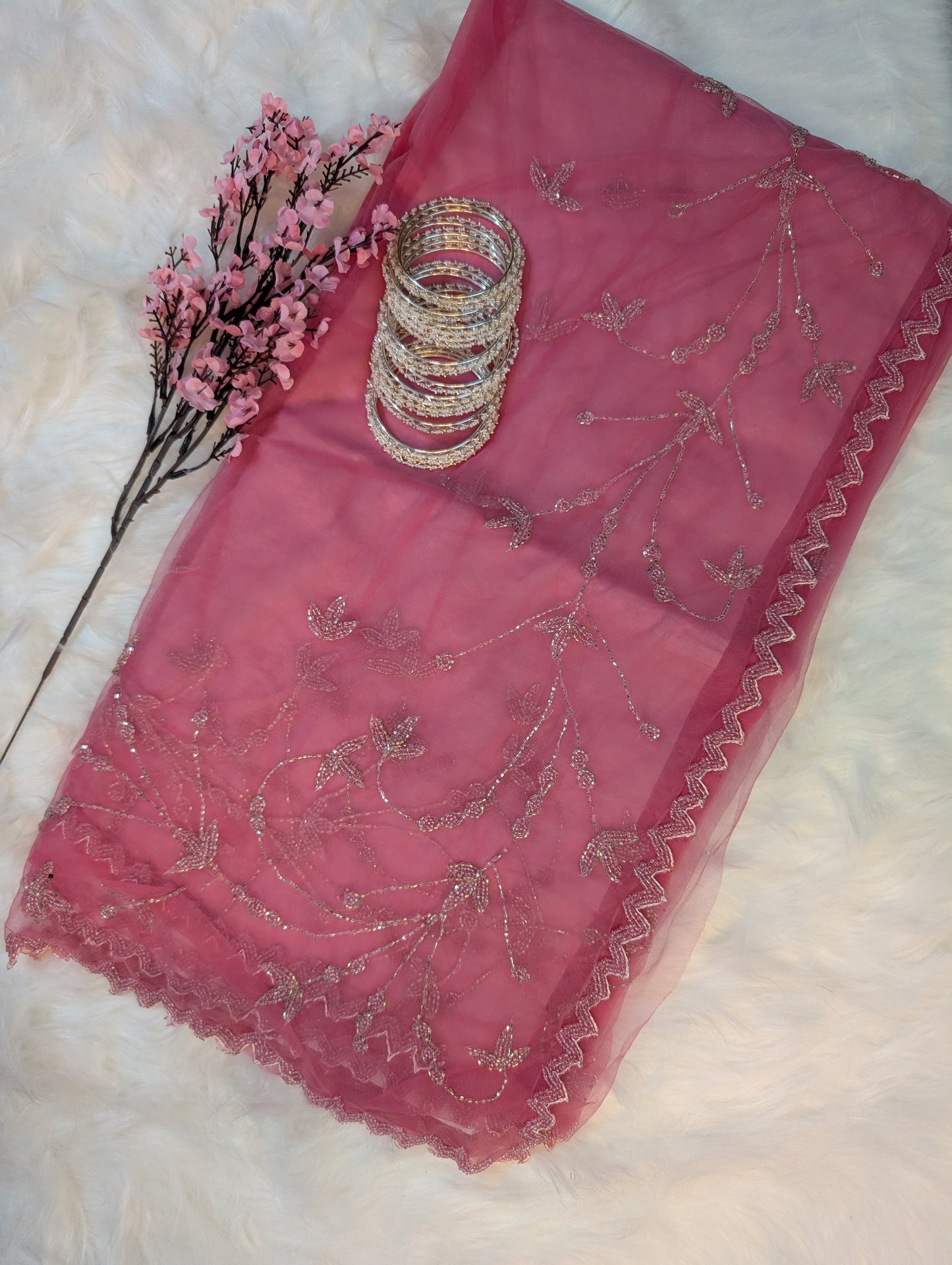 Pink embroidered fabric with gold patterns on a white background